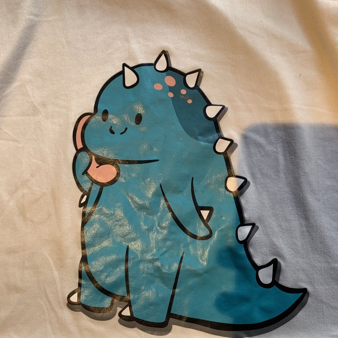 Blue Dinosaur White T-Shirt (Category: Tshirts & Polo Shirts ) located in Manila. Submitted by shardz07 (Listing ID 1470441646, Image 3). Description: selling since my my sister keeps on using this shirt 🤣 Issue: little wrinkly Little stain.