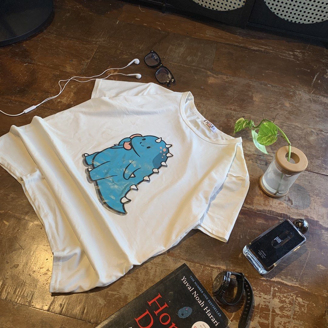 Blue Dinosaur White T-Shirt (Category: Tshirts & Polo Shirts ) located in Manila. Submitted by shardz07 (Listing ID 1470441646, Image 2). Description: selling since my my sister keeps on using this shirt 🤣 Issue: little wrinkly Little stain.