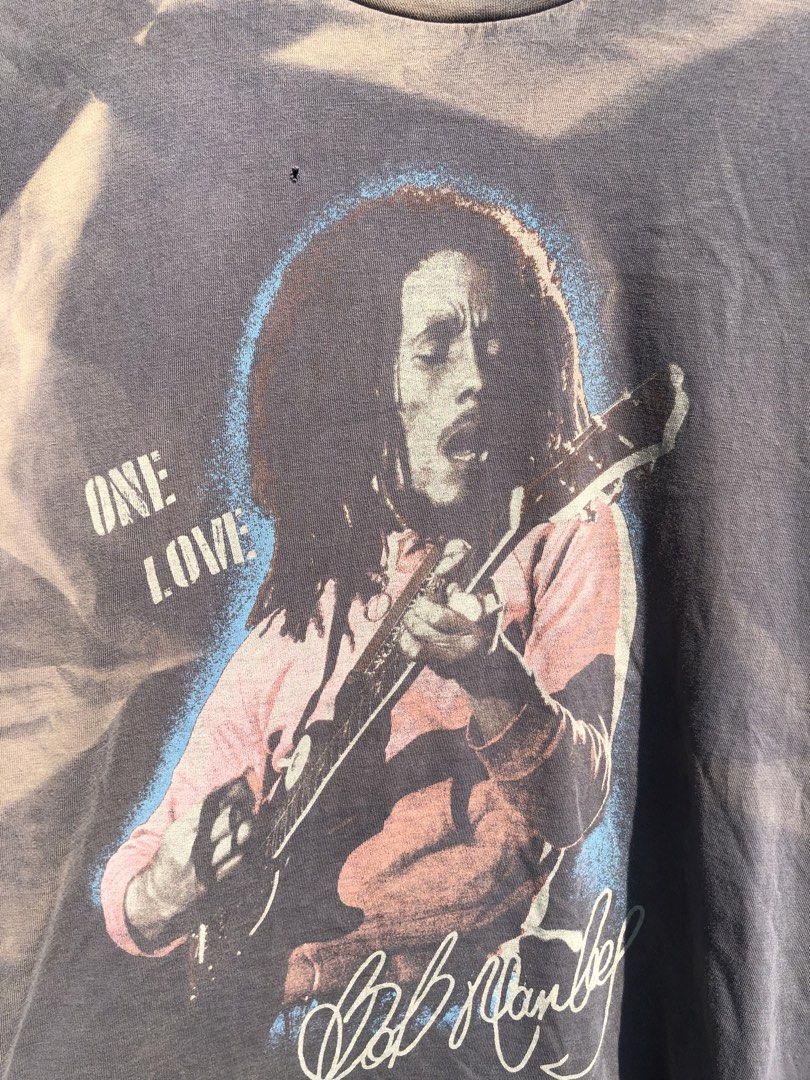 Bob Marley One Love Graphic Tee (Category: Tshirts & Polo Shirts ) located in San Jose. Submitted by mightycloud-7dc0 (Listing ID 1470410242, Image 2). Description: American Eagle crewneck t-shirt. Dark grey washed finish with heavy sun-faded areas. Front features a large Bob Marley graphic print with 'One Love' lettering and signature. Size small. Has one small hole near the neckline graphic as pictured. Soft vintage-style fabric with noticeable