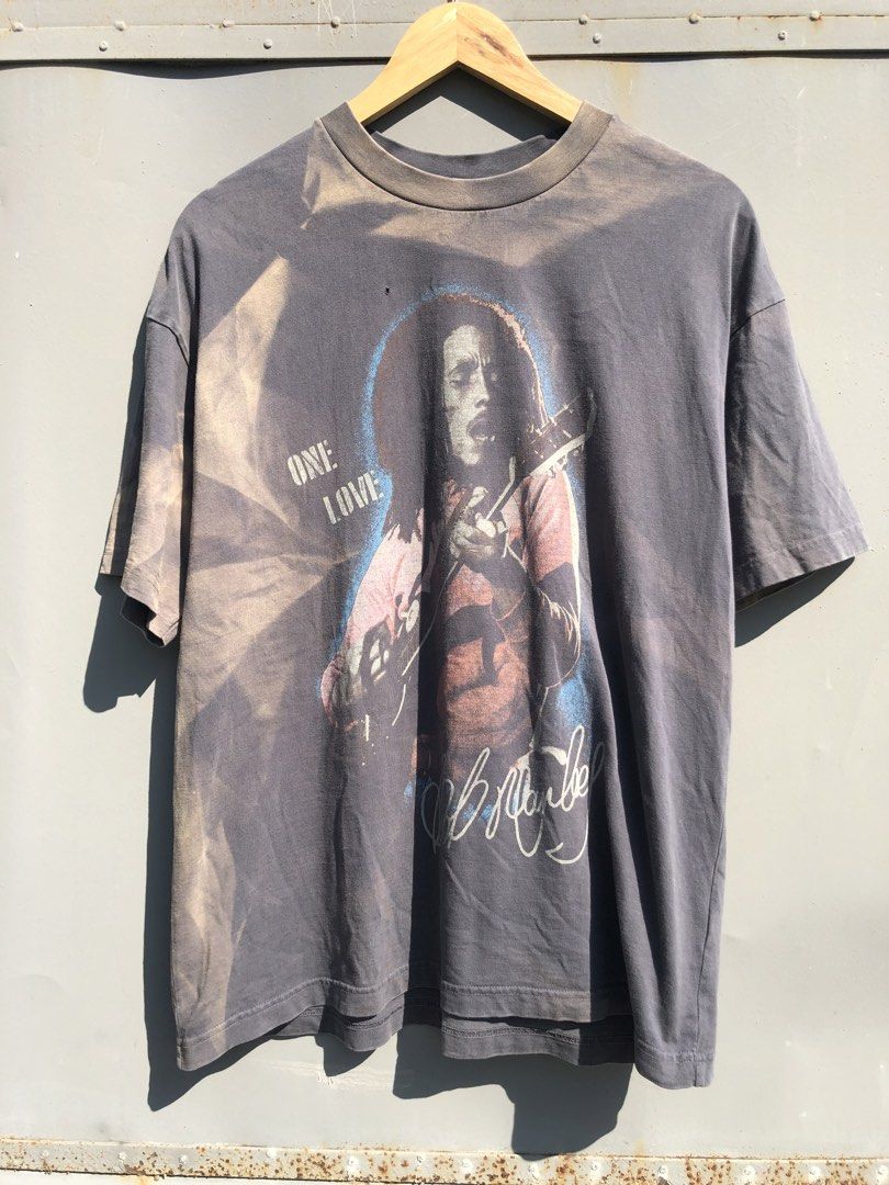 Bob Marley One Love Graphic Tee (Category: Tshirts & Polo Shirts ) located in San Jose. Submitted by mightycloud-7dc0 (Listing ID 1470410242, Image 1). Description: American Eagle crewneck t-shirt. Dark grey washed finish with heavy sun-faded areas. Front features a large Bob Marley graphic print with 'One Love' lettering and signature. Size small. Has one small hole near the neckline graphic as pictured. Soft vintage-style fabric with noticeable
