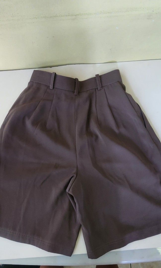 Brown high waisted tailored shorts pleated front (Category: Shorts) located in Quezon City. Submitted by amenohana (Listing ID 1470357135, Image 2). Description: - Color: Brown - Style: Tailored shorts with front pleats and relaxed fit - Length: Knee-length - Details: Waistband with belt loops and single button closure - Condition: Excellent, clean fabric with no stains or damage - Versatility: Great staple piece for warm weather or casual office