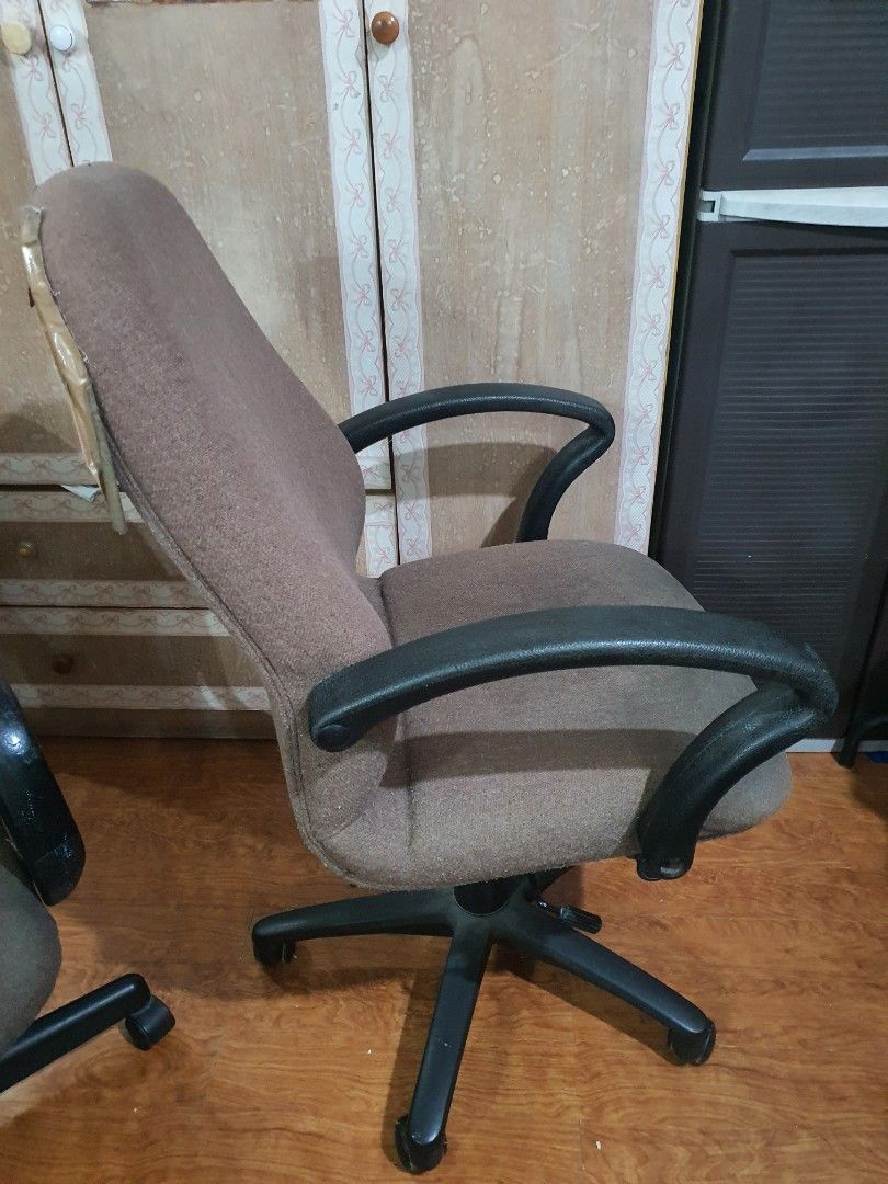 Brown Office Chair With Armrests And Wheels (Category: Office Furniture & Fixtures) located in Paranaque City. Submitted by nicessities (Listing ID 1470404137, Image 2). Description: - Brown upholstered office chair with black plastic armrests - Five-star wheeled base with fully functional rolling and swivel mechanism - Fabric features visible wear, staining, and tape repairs on the top and bottom edges - Great working condition, ideal for a budg