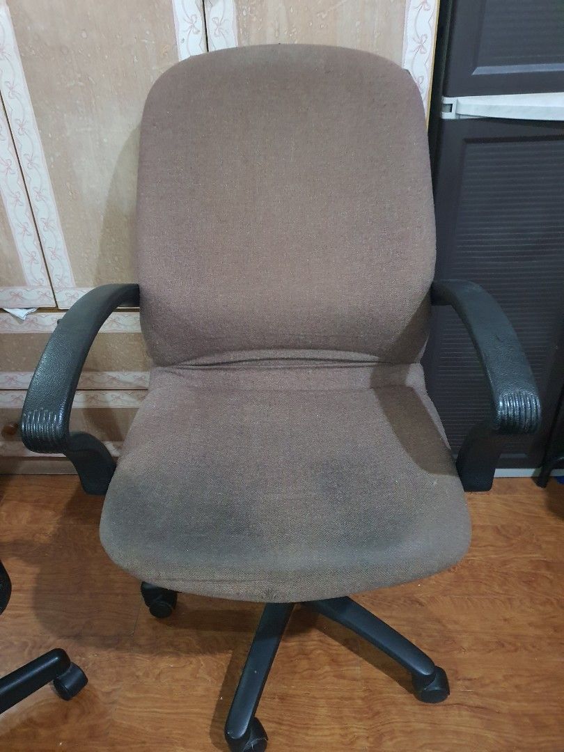 Brown Office Chair With Armrests And Wheels (Category: Office Furniture & Fixtures) located in Paranaque City. Submitted by nicessities (Listing ID 1470404137, Image 1). Description: - Brown upholstered office chair with black plastic armrests - Five-star wheeled base with fully functional rolling and swivel mechanism - Fabric features visible wear, staining, and tape repairs on the top and bottom edges - Great working condition, ideal for a budg