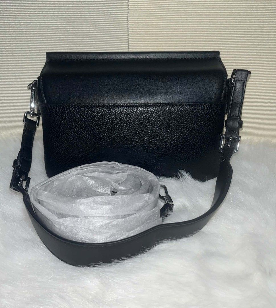 Calvin Klein 2-Way Sling Bag Black (Category: Cross-body Bags) located in Imus. Submitted by maria_pilayo (Listing ID 1470435294, Image 2). Description: - Brand: Calvin Klein - 💯 % Authentic - Color: Solid black with chic silver-tone hardware branding - Dimensions: 23cm (L) x 17cm (H) x 3.5cm (W) - Design: Structured bottom panel in textured leather - Extras: Includes an additional adjustable strap, still sealed in original protective plastic pa