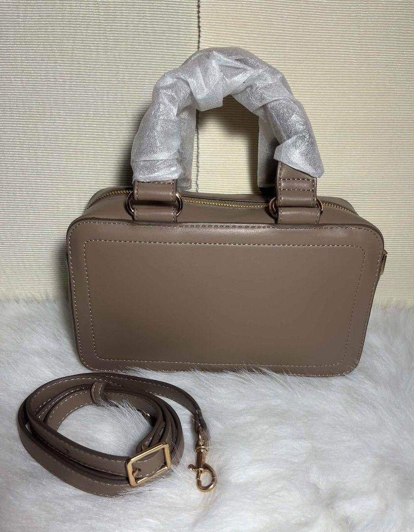 Calvin Klein Camera Bag Dessert Taupe (Category: Luxury Bags & Wallets) located in Imus. Submitted by maria_pilayo (Listing ID 1470435797, Image 2). Description: - Brand: Calvin Klein - 💯 % Authentic - Style: Camera bag - Color: Dessert Taupe - Dimensions: 23.5cm (L) x 13.5cm (H) x 8cm (W) - Condition: Brand new, never used (handle wrapping still intact) - Features: Front monogram logo, gold-tone hardware, and top zip closure - Straps: Double to