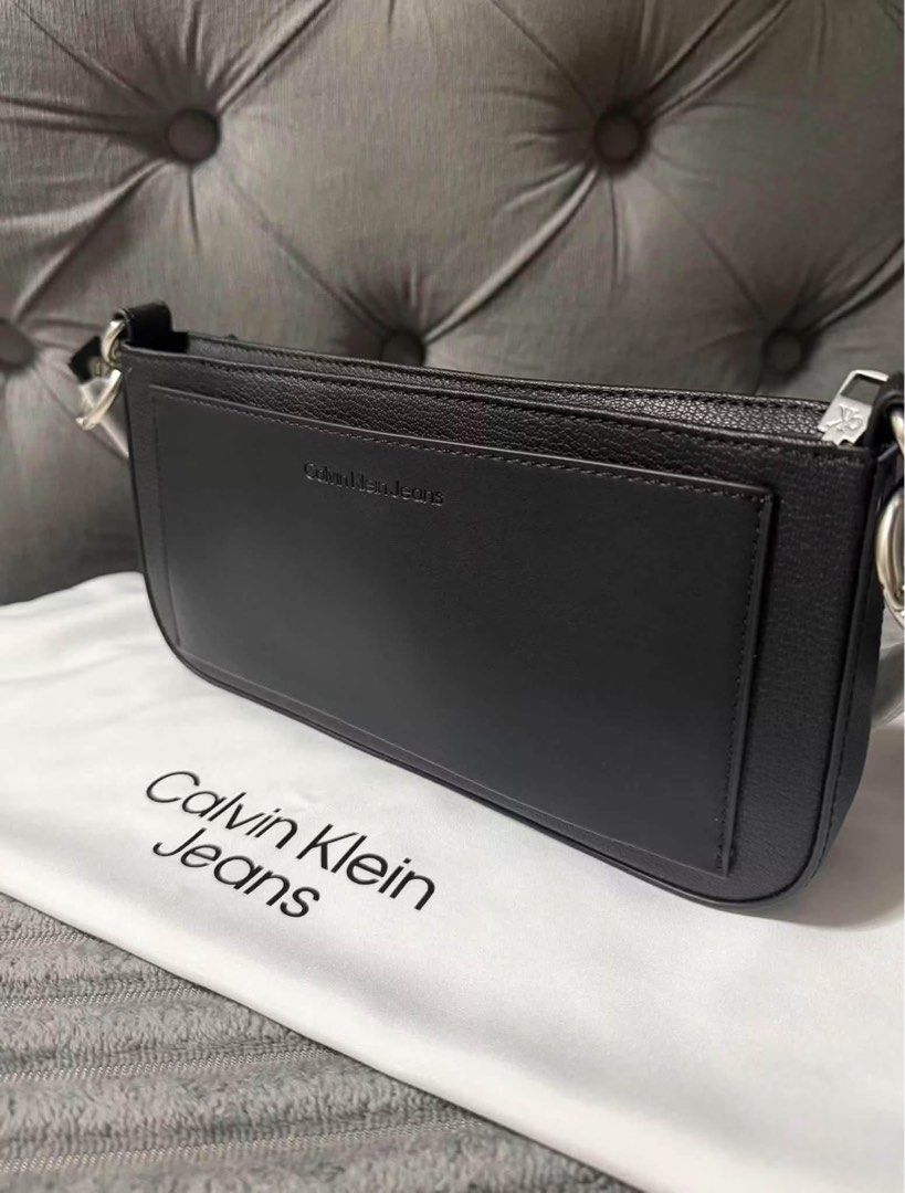Calvin Klein Jeans Black Shoulder Bag (Category: Shoulder Bags) located in Calamba. Submitted by saiphsavion (Listing ID 1470451334, Image 3). Description: - Brand: Calvin Klein Jeans - Color: Classic Black - Material: Textured faux leather with silver metallic CK logo - Closure: Secure top zip - Interior: Fabric-lined with convenient slip pocket - Inclusions: Original store tags attached and branded dust bag included - Condition: Brand new, 100%