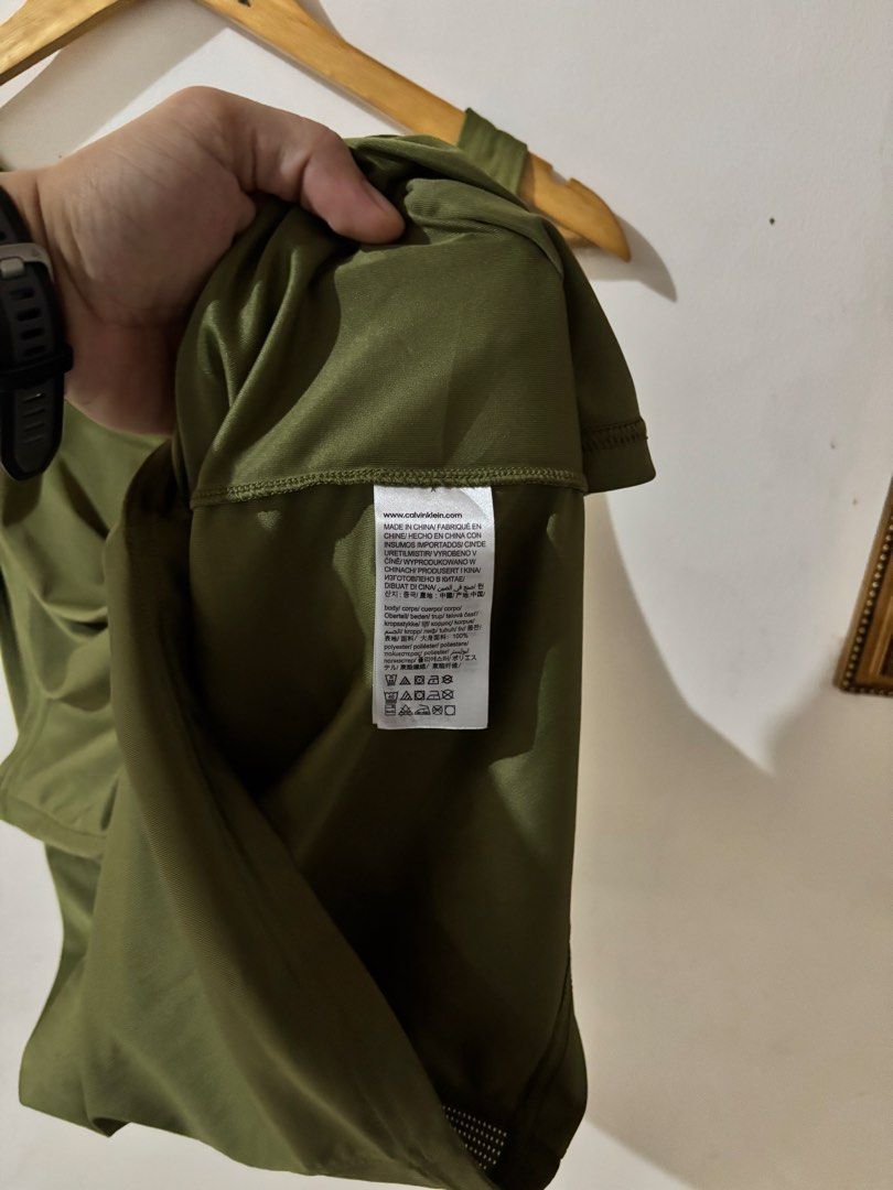 Calvin Klein Performance Olive Green Tank Top Size M (Category: Sleeveless) located in Kalibo. Submitted by mack29 (Listing ID 1470351397, Image 2). Description: - Brand: Calvin Klein Performance - Color: Olive Green - Size: Medium - Material: 100% Polyester (breathable) - Design: CK logo on chest, large reflective Calvin Klein branding down the back spine - Feature: Vertical breathable mesh panel running down the back - Best for: Workouts, gym s