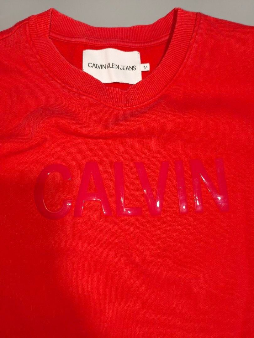 Calvin Klein Red Sweatshirt (Category: Coats, Jackets and Outerwear) located in Pasig City. Submitted by tobyrama (Listing ID 1470537452, Image 2). Description: ✔️ Brand: Calvin Klein Jeans ✔️ Design: Long Sleeve Shirt ✔️ Color: Red ✔️ Size: Medium (on tag) ✔️ Condition: Almost New it has washable stains ✔️ Dimensions: length: 20 inches width: 20 inches sleeves length: 22 inches sleeves width: 4 inches Can do J&T shipping or Lalamove for same day