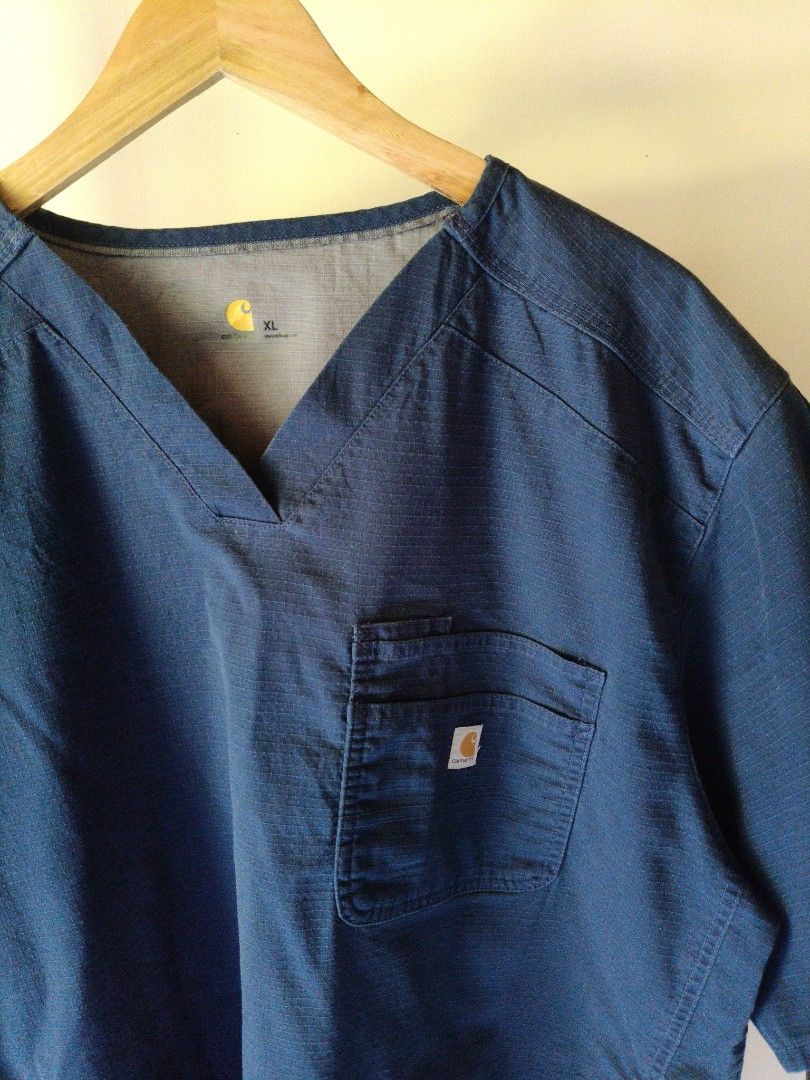 Carhartt Navy Blue Scrub Top XL (Category: Activewear) located in Dumaguete. Submitted by happyocean_14dac6 (Listing ID 1470367300, Image 3). Description: - Brand: Carhartt - Color: Navy Blue - Size: XL - Style: V-neck, short sleeves - Features: Front chest pocket with Carhartt logo patch, textured fabric - Origin: Made in Bangladesh - Condition: Clean interior and side care tags.
