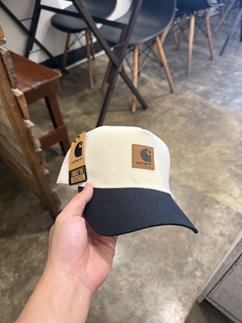Carhartt Trucker Hat Off White Black Snapback (Category: Caps & Hats) located in Pozorrubio. Submitted by kulin_ (Listing ID 1470495800, Image 1). Description: - Brand: Carhartt - Condition: Brand new with original tag attached - Color: Off-white and black - Design: Structured front with a curved brim and breathable mesh back panels - Details: Classic brown leather Carhartt logo patch on the front - Fit: Adjustable white snapback closure.