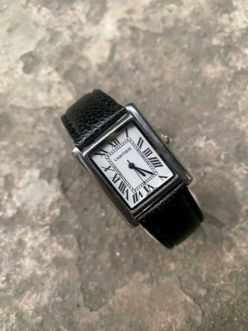 Cartier Tank Watch with Black Leather Strap (Category: Luxury Watches) located in Caloocan City. Submitted by cadalojohn65897 (Listing ID 1470383453, Image 1). Description: - Brand: Cartier Tank - Case: Classic rectangular silver-tone case - Dial: White dial with black Roman numerals and dark blue hands - Crown: Features a signature small blue stone detail - Strap: Black textured leather strap - Movement: Battery-powered (Quartz) - Origin: Swiss 