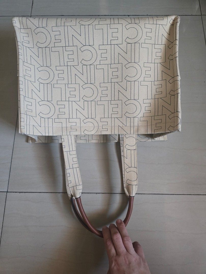 Celine Canvas Tote Bag with (Category: Tote Bags) located in Manila. Submitted by brandedshoppe_mnl (Listing ID 1470554301, Image 2). Description: -Authentic Celine tote bag in cream canvas with all-over logo print and brown leather handles. -Preloved and in good cpndition -Large Triomphe emblem on the front. -Structured rectangular shape with flat base. - Includes a black Celine dust bag. Clean canvas inside and out, sturdy leather top handles..