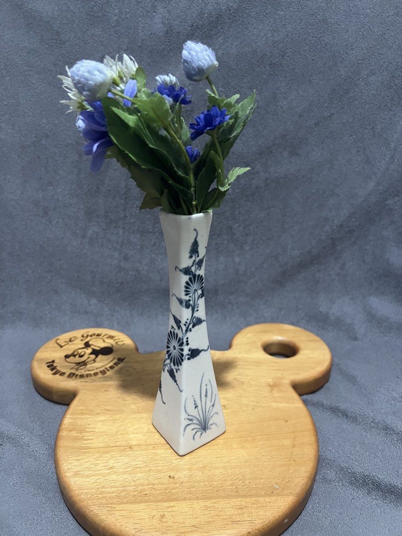 Ceramic Bud Vase flower not included (Category: Vases & Decorative Bowls) located in Las Pinas. Submitted by maple0305 (Listing ID 1470497971, Image 2). Description: - Type: Ceramic bud vase with square base and narrowing neck - Design: Classic blue and white floral painting with a crackle glaze finish - Inclusions: Comes with a small artificial flower arrangement (blue, purple, white with green stems) - Height: Approx. 20 cm total (including flo