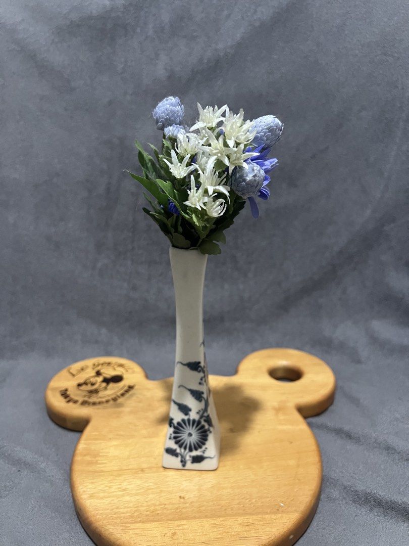 Ceramic Bud Vase flower not included (Category: Vases & Decorative Bowls) located in Las Pinas. Submitted by maple0305 (Listing ID 1470497971, Image 1). Description: - Type: Ceramic bud vase with square base and narrowing neck - Design: Classic blue and white floral painting with a crackle glaze finish - Inclusions: Comes with a small artificial flower arrangement (blue, purple, white with green stems) - Height: Approx. 20 cm total (including flo