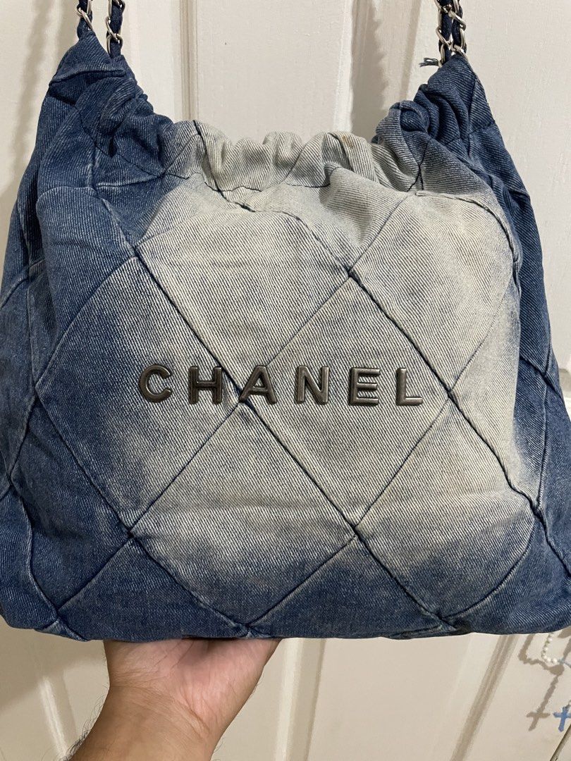 Chanel Denim Quilted Shoulder Bag (Category: Luxury Bags & Wallets) located in Naga. Submitted by thriftboss88 (Listing ID 1470481706, Image 3). Description: - Brand: Chanel - Material: Blue and light wash denim - Design: Quilted diamond pattern with bold Chanel front lettering - Hardware & Straps: Silver-tone interwoven chain with leather and a branded round metal charm - Closure: Open top with gathered drawstring detail - Condition: Excellent (