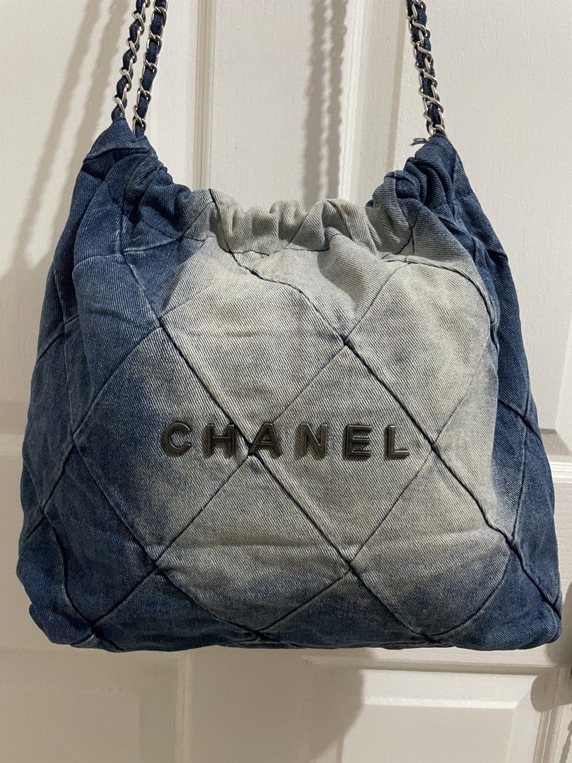 Chanel Denim Quilted Shoulder Bag (Category: Luxury Bags & Wallets) located in Naga. Submitted by thriftboss88 (Listing ID 1470481706, Image 2). Description: - Brand: Chanel - Material: Blue and light wash denim - Design: Quilted diamond pattern with bold Chanel front lettering - Hardware & Straps: Silver-tone interwoven chain with leather and a branded round metal charm - Closure: Open top with gathered drawstring detail - Condition: Excellent (