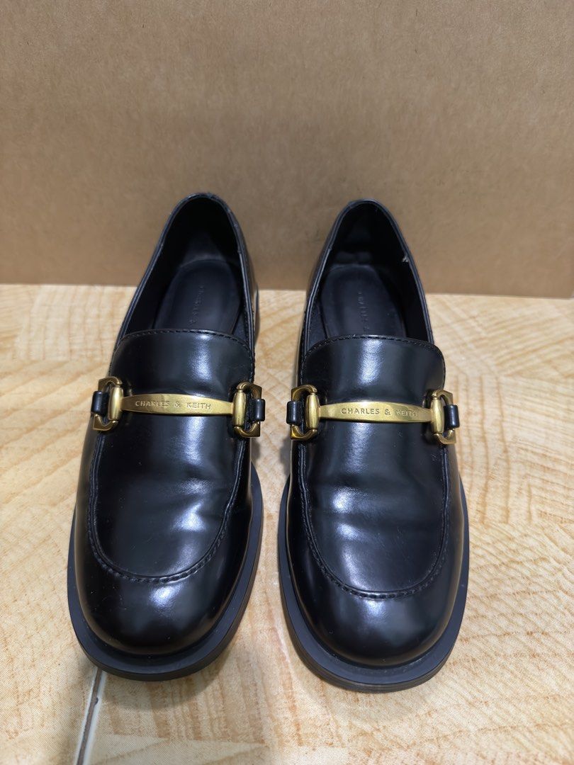 Charles & Keith Black Loafers with Gold Hardware (Category: Loafers) located in Muntinlupa City. Submitted by sellesayo08 (Listing ID 1470357310, Image 1). Description: Classic black loafers from Charles & Keith. Gold-tone metal hardware across the front strap. Chunky platform sole with a small heel. Slip-on design. Minimal creasing on the leather upper from normal wear. Clean interior lining. Solid construction, sturdy rubber soles..