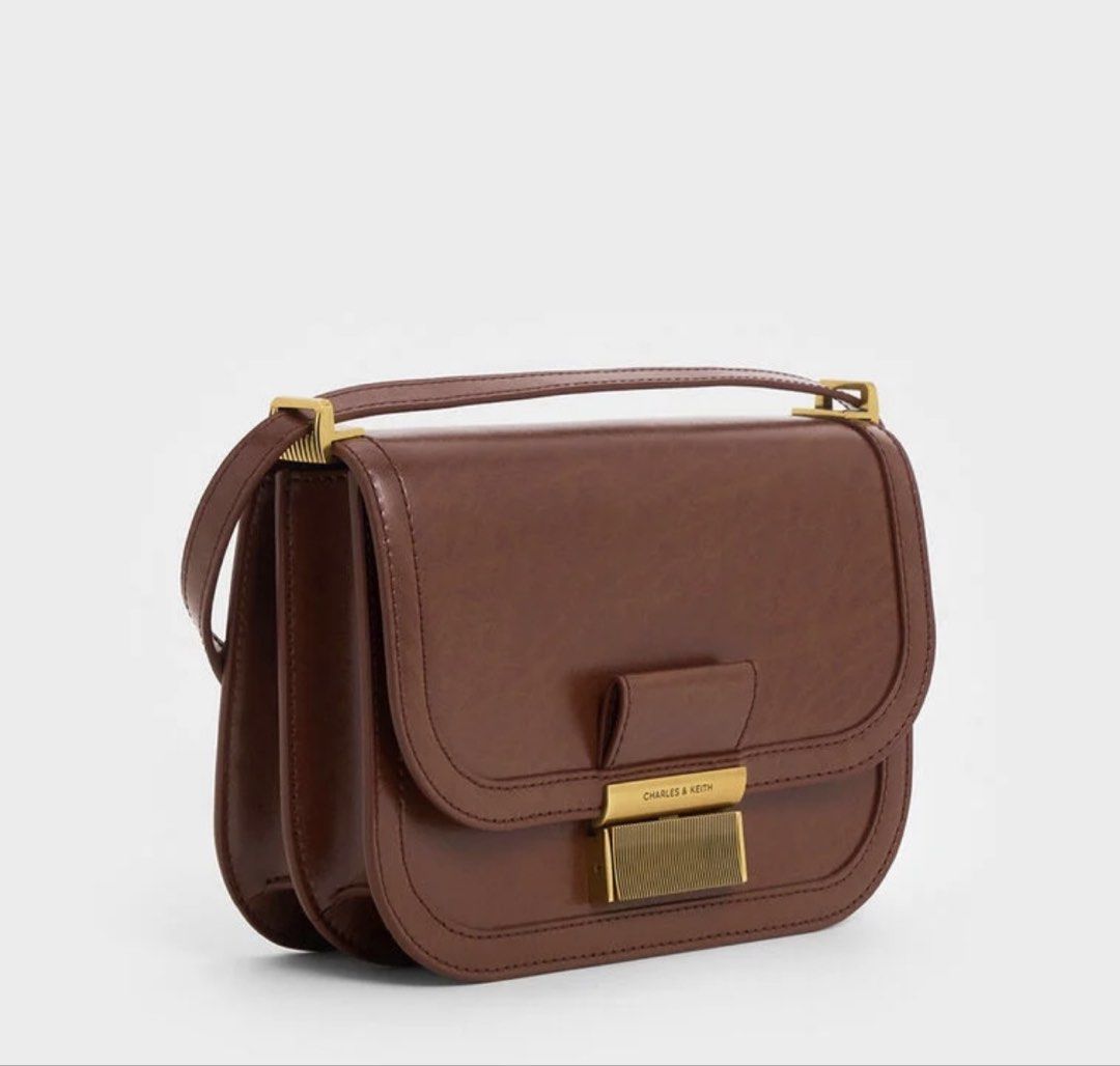 Charles & Keith Charlot Bag Dark Brown (Category: Cross-body Bags) located in Pasay City. Submitted by sggma (Listing ID 1470491274, Image 2). Description: - Brand: Charles & Keith - Style: Charlot Bag (Classic saddle shape) - Color: Dark Brown with brushed gold hardware - Closure: Secure push-lock - Strap: Includes adjustable shoulder strap - Condition: Clean inside and out, very well maintained - Features: Rich texture finish, spacious enough f