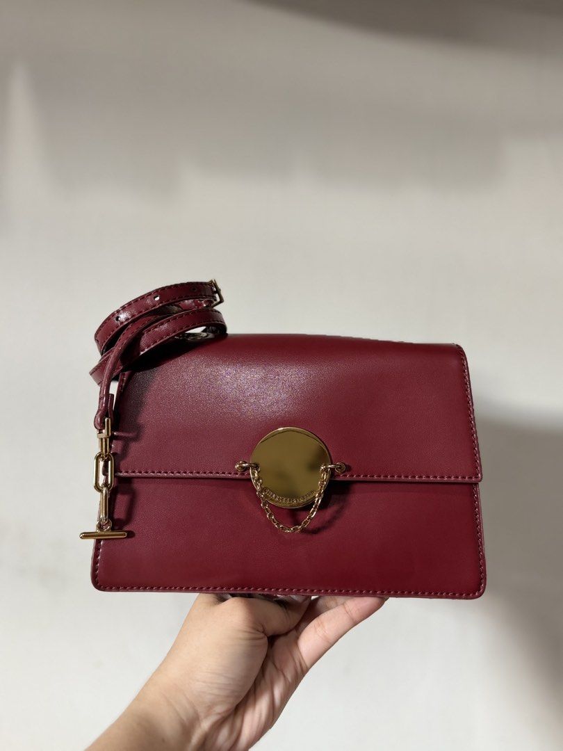 Charles & Keith Maroon Crossbody Bag (Category: Cross-body Bags) located in Lipa City. Submitted by asleeeh (Listing ID 1470349278, Image 1). Description: - Brand: Charles & Keith - Color: Rich maroon with elegant gold-tone hardware - Style: Crossbody bag featuring a stylish chain accent and round closure detail - Strap: Includes an adjustable strap for a customized fit - Storage: Convenient back zip pocket and interior zipped compartment - Inter