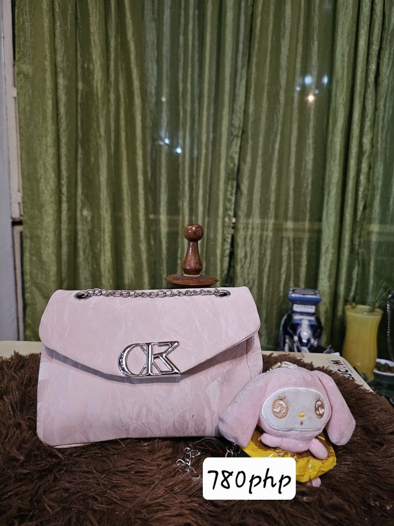 CK Pink Shoulder Bag with Plush Charm (Category: Shoulder Bags) located in Pagadian. Submitted by buyhere888 (Listing ID 1470473794, Image 1). Description: - Authentic pink shoulder bag with structured shape - Features eye-catching metallic CK logo hardware on the front flap - Elegant chain strap for versatile wear - Textured pink material for a chic look - Comes with an adorable matching pink plush bunny charm.