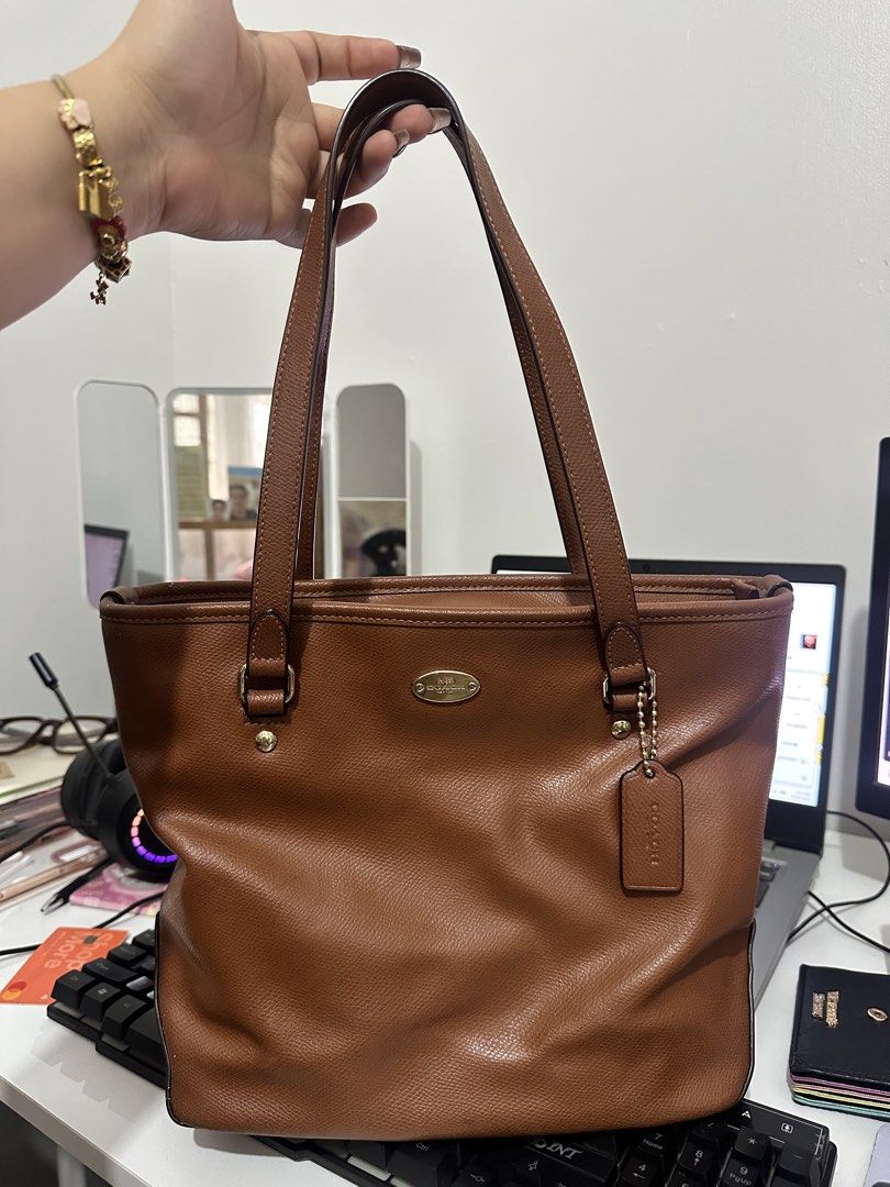 Coach City Zip Tote (Category: Luxury Bags & Wallets) located in Quezon City. Submitted by stella.g (Listing ID 1470402698, Image 1). Description: - Authentic Coach brown leather tote bag in Excellent condition - Elegant gold-tone hardware with front metal logo plaque - Secure zip-top closure and exterior back zip pocket - Comfortable double shoulder straps with a sturdy drop length - Structured flat bottom allows the bag to stand upright on its 