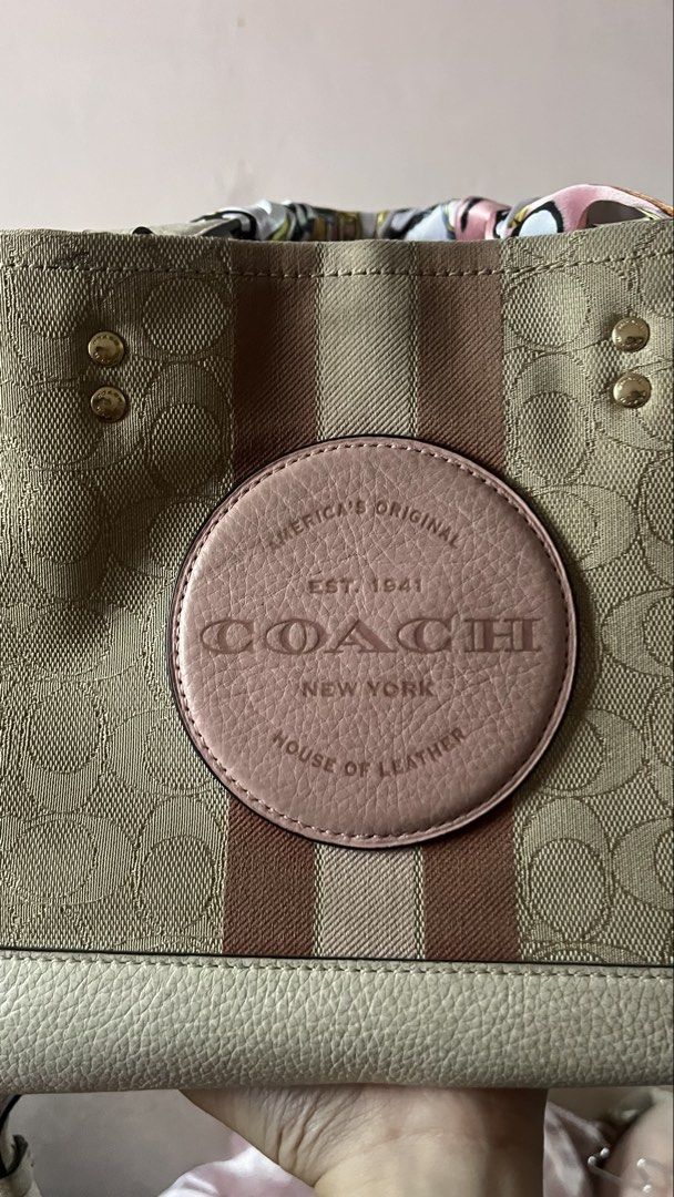 Coach Dempsey Carryall Slingbag (Category: Tote Bags) located in Davao. Submitted by kanto-10 (Listing ID 1470378117, Image 2). Description: - Authentic Coach signature canvas tote bag - Cream base with chic pink and brown vertical stripes - Features a round leather patch logo and luxury gold-tone hardware - Spacious interior compartment with dark lining - Includes a detachable crossbody strap for versatile wear - Comes with a stylish pink patter
