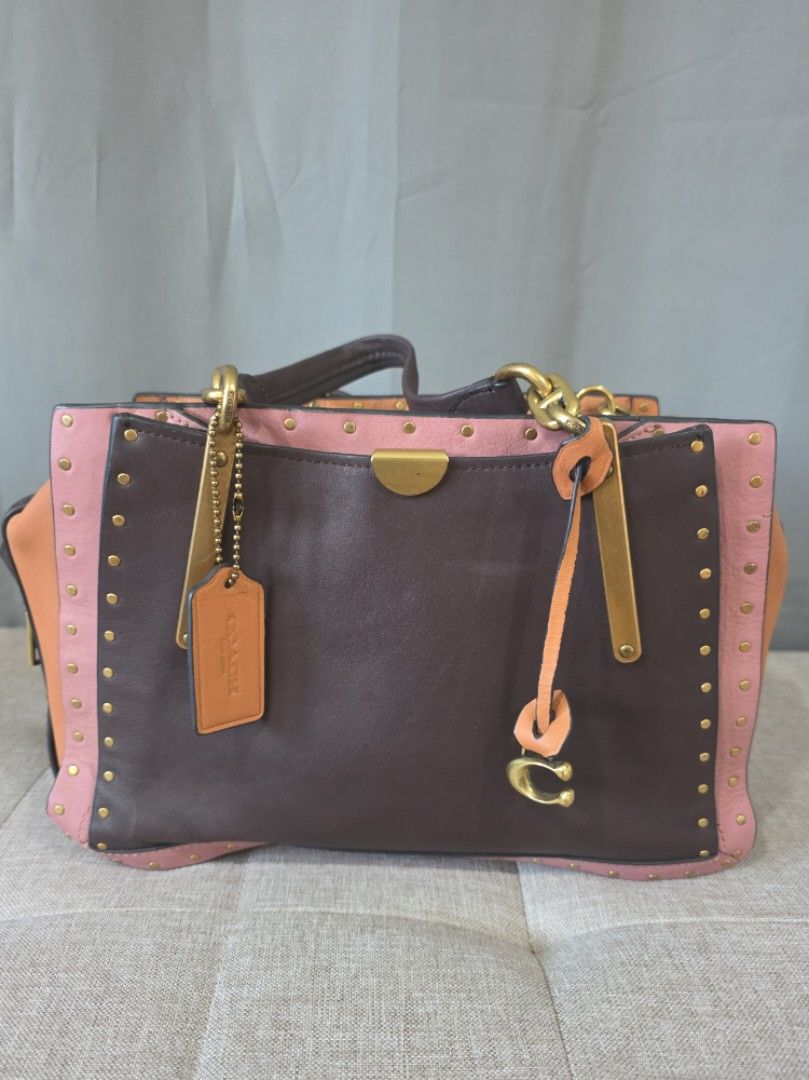 Coach Rogue Bag (Category: Luxury Bags & Wallets) located in Binan City. Submitted by karosellescloset (Listing ID 1470422110, Image 1). Description: Coach 1941 Rogue Bag featuring a studded colorblock design in leather and suede trim. ​Key defining features include: ​Model Line: Coach 1941 Rogue (Satchel / Tote). ​Design Details: Colorblocked leather panels (dark brown center body, pink trim, and orange/peach side gussets), brass hardware, borde