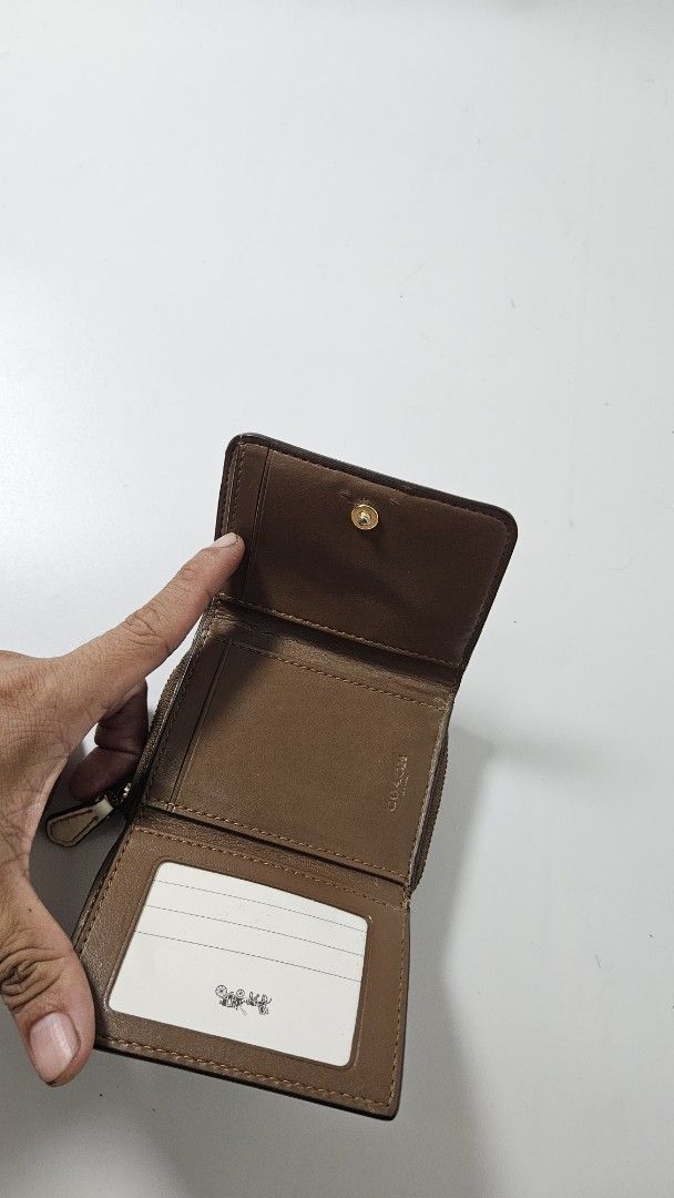 Coach Signature Canvas Small Tri-fold Wallet Brown (Category: Luxury Bags & Wallets) located in Alfonso. Submitted by jbcamet (Listing ID 1470401982, Image 3). Description: - Brand: Coach - Material: Signature brown coated canvas with smooth brown leather lining - Design: Tri-fold with secure snap closure - Features: Clear ID window, multiple card slots, full-length bill compartment, and side zippered coin pocket - Condition: Clean with normal si