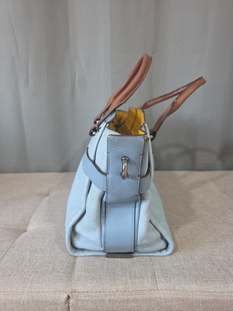 Coach Swagger Carryall (Category: Luxury Bags & Wallets) located in Binan City. Submitted by karosellescloset (Listing ID 1470423440, Image 2). Description: Coach Swagger 27 Carryall in pebble leather. ​Key Details & Identification: ​Model Name: Coach Swagger 27 Carryall / Satchel ​Colorway: Colorblock light blue/ice blue leather body with tan brown handles, gunmetal hardware, and a yellow interior lining. ​Signature Features: ​Double-turnlock ac