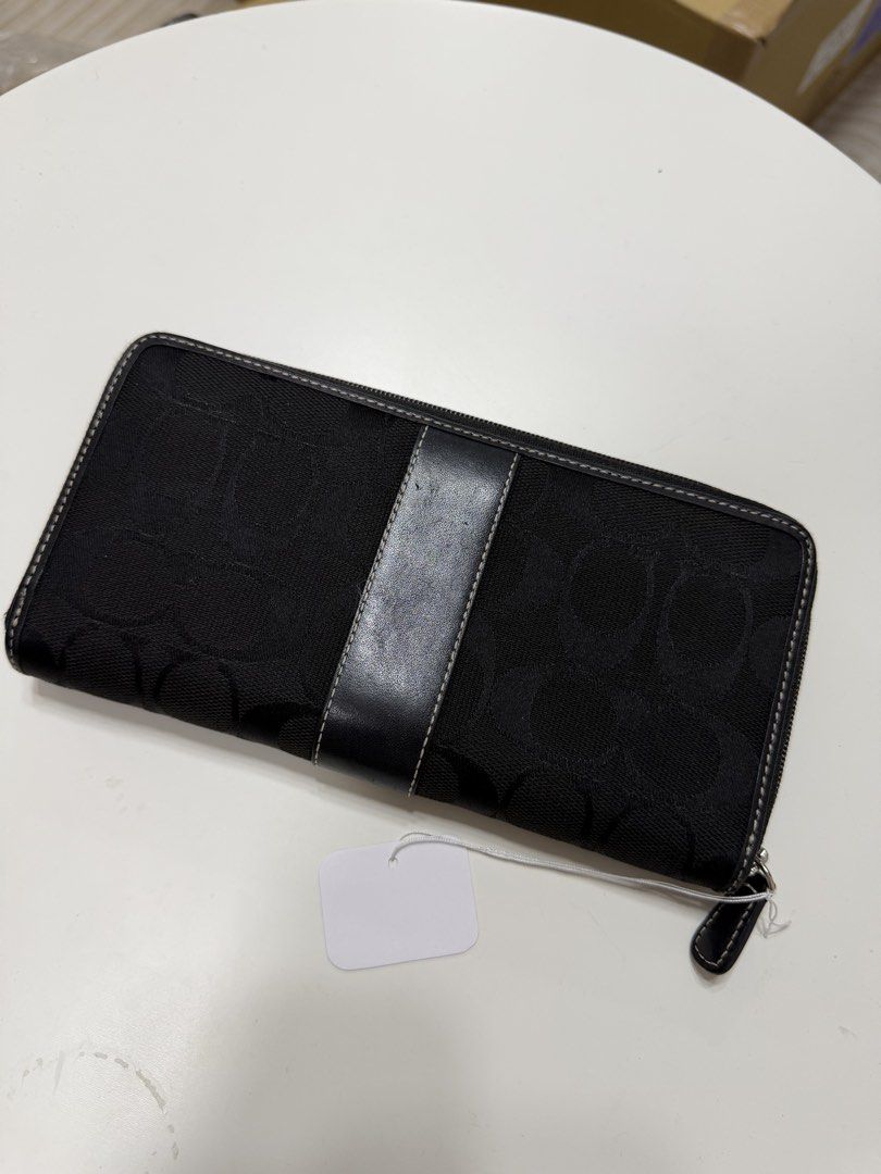 Coach wallet (Category: Wallets & Card holders) located in Cavite. Submitted by aljennaaaa (Listing ID 1470542454, Image 2). Description: - Authentic Coach zip-around wallet - Black signature C fabric with center leather stripe and debossed logo patch - Multiple card slots and slip compartments for organization - Secure zippered coin pocket - Smooth black leather lining - Clean condition, inside and out - Standard zip closure with leather pull ta