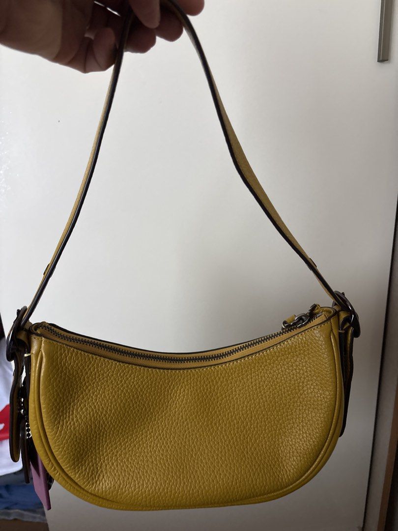 Coach Yellow Leather Shoulder Bag (Category: Luxury Bags & Wallets) located in Bulacan. Submitted by emgjoanag44033 (Listing ID 1470391729, Image 3). Description: - Brand: Coach - Color: Bright yellow with dark brown straps and hardware - Material: Premium pebbled leather - Style: Curved crescent shoulder bag - Closure: Top zipper - Features: Signature hangtag attached, clean interior lining - Size: Compact, fits daily essentials easily.