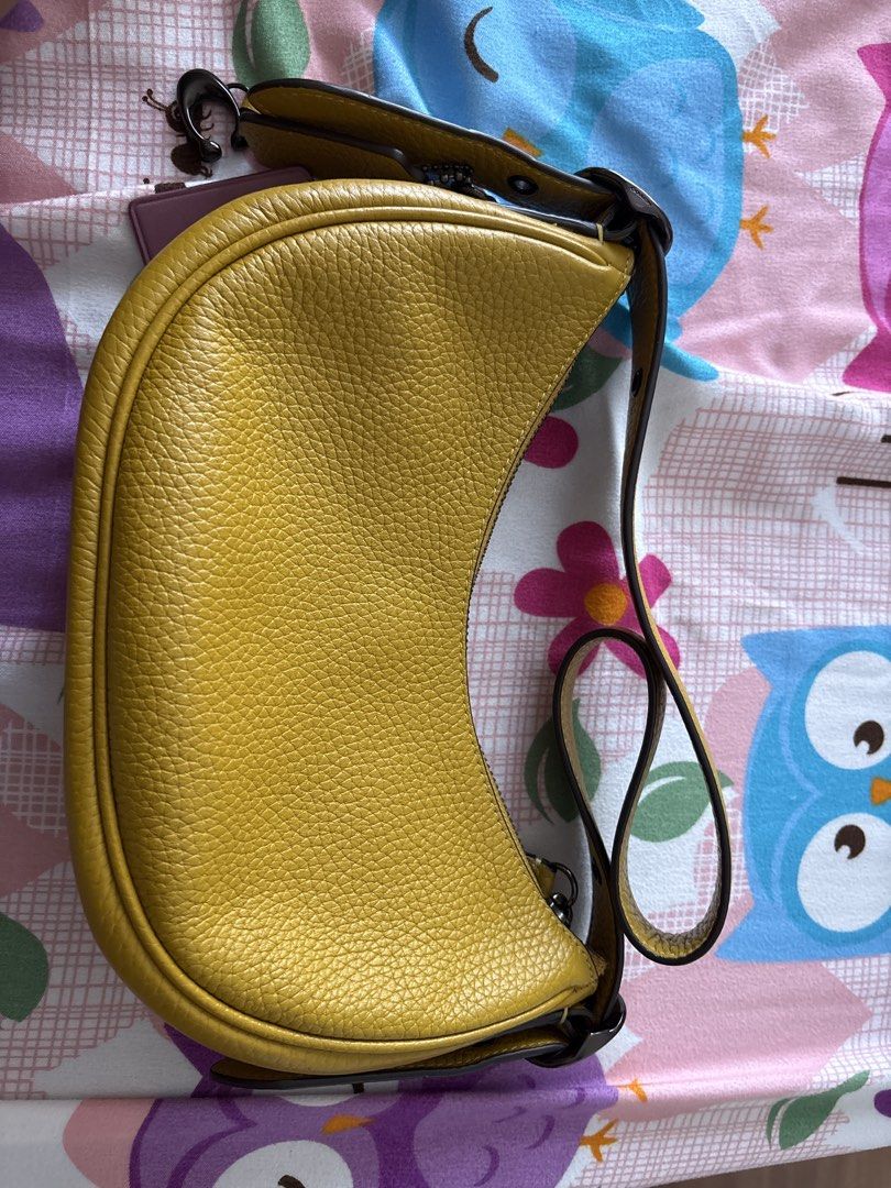 Coach Yellow Leather Shoulder Bag (Category: Luxury Bags & Wallets) located in Bulacan. Submitted by emgjoanag44033 (Listing ID 1470391729, Image 1). Description: - Brand: Coach - Color: Bright yellow with dark brown straps and hardware - Material: Premium pebbled leather - Style: Curved crescent shoulder bag - Closure: Top zipper - Features: Signature hangtag attached, clean interior lining - Size: Compact, fits daily essentials easily.