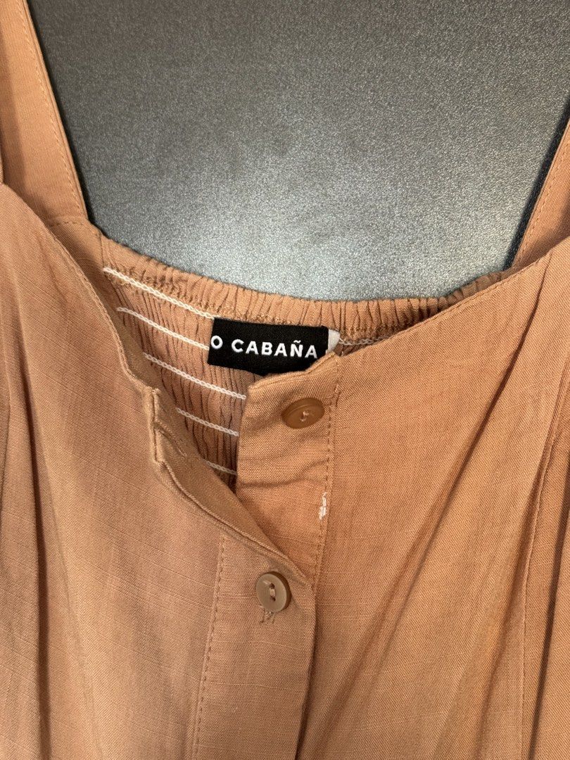 Coco Cabaña Brown Button-Down Summer Dress (Category: Dresses) located in Dasmarinas. Submitted by akelvin23 (Listing ID 1470429557, Image 3). Description: - Brand/Style: Coco Cabaña midi dress - Color: Neutral brown - Details: Square neckline, thick straps, gathered bodice, and matching front buttons - Fit: Fitted waist with a smocked back panel for flexibility - Skirt: Tiered, flowy design with a slight high-low hem - Fabric: Lightweight and te