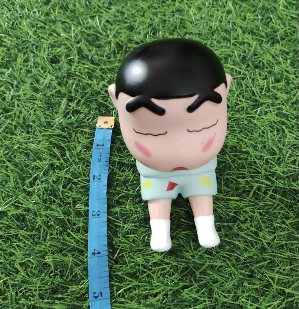 Crayon Shin-chan Figure Sleeping Pajamas (Category: Designer & Blind Box Toys) located in Makati City. Submitted by rare_thrift_stuff (Listing ID 1470359886, Image 1). Description: - Character: Crayon Shin-chan - Design: Sleeping pose wearing light blue pajamas with geometric shapes and pink cheeks - Size: Approximately 4 inches tall - Condition: Pre-loved with minor scuff marks and discoloration on the fingertips/hands (refer to close-up photo) 