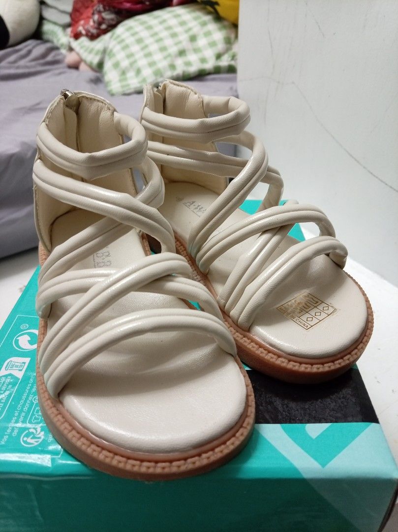Cream Strappy Flat Sandals (Category: Babies & Kids Fashion) located in Manila. Submitted by zeepheobee (Listing ID 1470436683, Image 1). Description: - Color: Cream with clean white insoles and a textured brown tread - Style: Crisscross straps across the top of the foot and around the ankle - Closure: Convenient back zipper for easy slip-on and off - Sole: Flat sole with good grip - Perfect staple footwear for summer outfits.