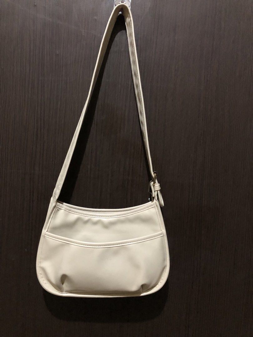 Cream White Shoulder Bag with Front Pocket (Category: Shoulder Bags) located in Valenzuela. Submitted by nixs2722 (Listing ID 1470504709, Image 1). Description: - Color: Cream white - Material: Premium faux leather - Design: Curved, slouchy body with gold-tone metal buckle - Features: Exterior front slip pocket and clean interior lining - Strap: Single adjustable strap - Capacity: Easily fits a standard long wallet - Style: Perfect for casual dai