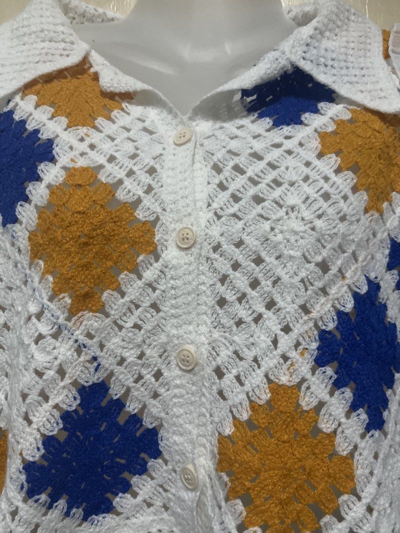 Crochet Granny Square Button-Up Blouse White Blue Yellow (Category: Blouses) located in Tabuk. Submitted by zenwolf-1867 (Listing ID 1470532066, Image 3). Description: - Handmade-style crochet granny square blouse - White base with blue and mustard yellow patches - Collared neckline with front button closure - Long sheer chiffon sleeves with ruffled shoulders and elastic cuffs - Trendy cropped fit - Unique vintage statement piece, perfect for lay