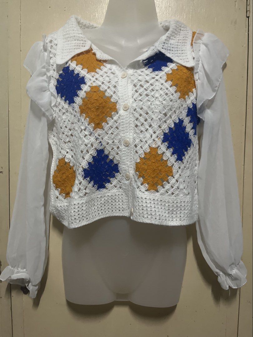 Crochet Granny Square Button-Up Blouse White Blue Yellow (Category: Blouses) located in Tabuk. Submitted by zenwolf-1867 (Listing ID 1470532066, Image 2). Description: - Handmade-style crochet granny square blouse - White base with blue and mustard yellow patches - Collared neckline with front button closure - Long sheer chiffon sleeves with ruffled shoulders and elastic cuffs - Trendy cropped fit - Unique vintage statement piece, perfect for lay