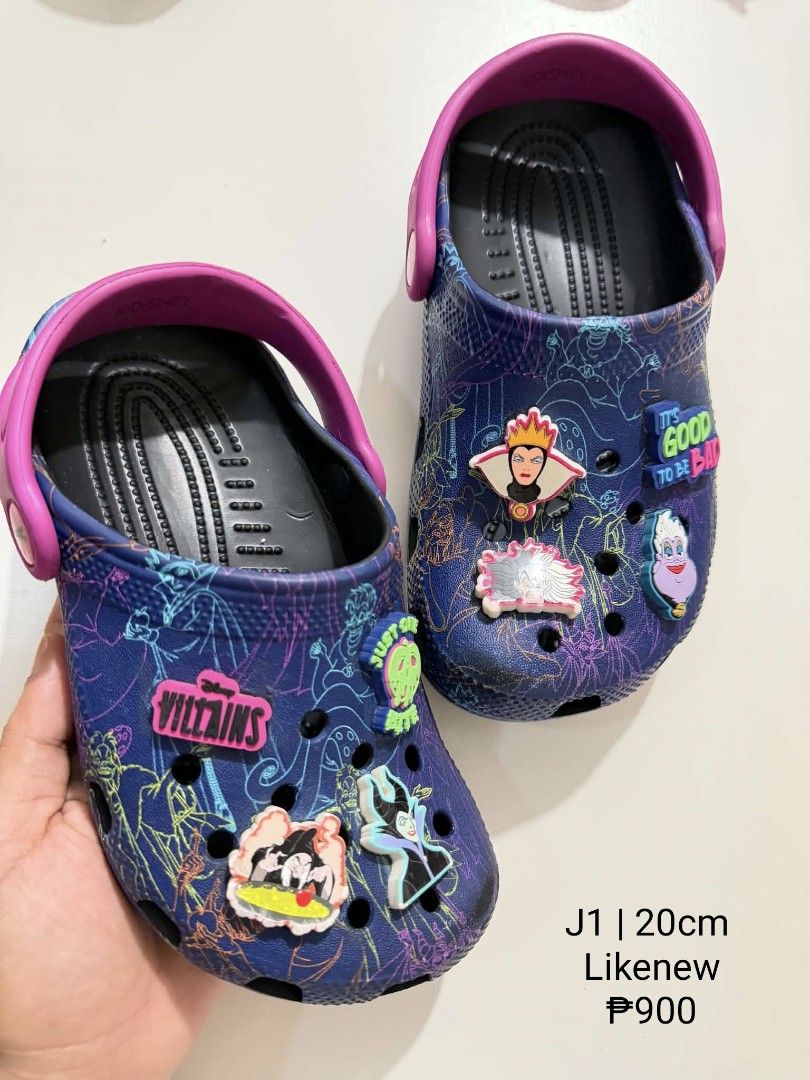 Crocs J1 (Category: Babies & Kids Fashion) located in San Fabian. Submitted by hbrst1998 (Listing ID 1470358245, Image 1). Description: - Authentic Disney Villains printed clogs in dark blue - Features contrasting pink backstraps - Decorated with multiple Jibbitz charms (Ursula, Maleficent, Queen of Hearts, and Villains logo) - Size: J1 (fits 20cm feet) - Condition: Clean inside and out, sanitized, and ready to wear - Perfect for Disney fans and 