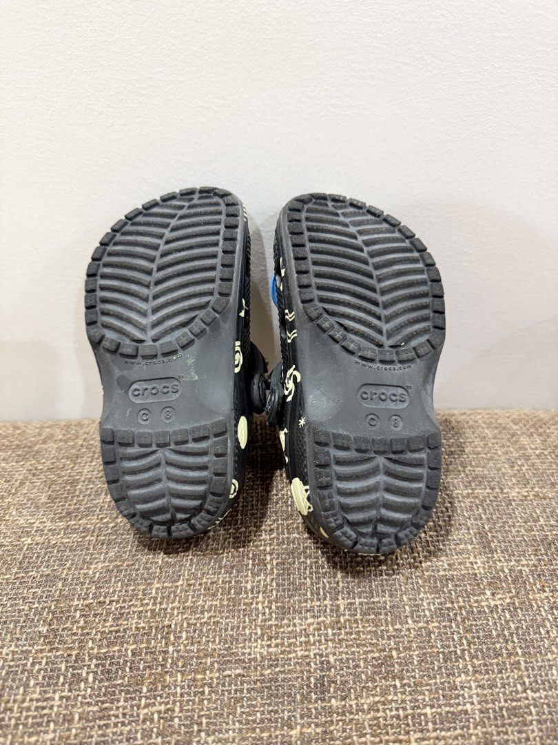 Crocs Toddler Classic Glow Space Clog C8 Black (Category: Babies & Kids Fashion) located in Pasig City. Submitted by abbbbbbbi (Listing ID 1470410765, Image 2). Description: - Brand/Model: Crocs Toddler Classic Glow Space Clog - Color: Black - Size: C8 - Design: Glow-in-the-dark space theme (stars, planets, rockets) with pre-attached colorful Jibbitz charms - Features: Easy slip-on style with secure heel straps - Condition: Worn only a few times,