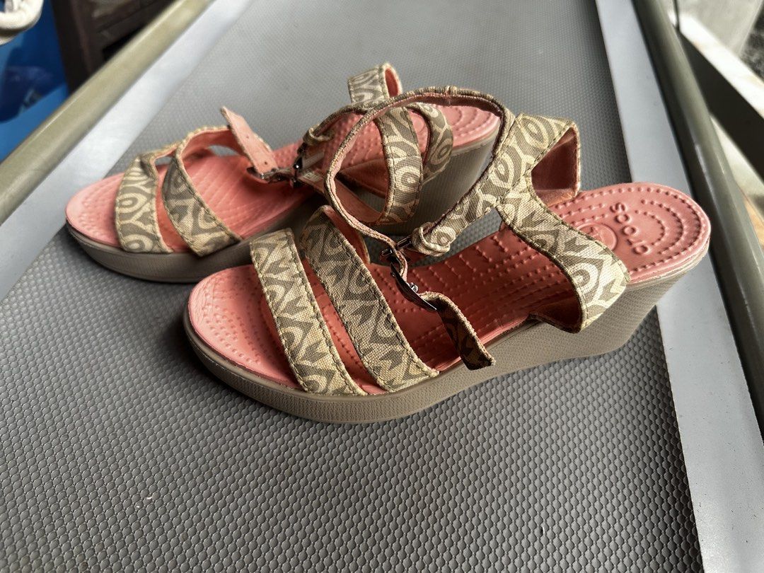 Crocs Wedge Sandals Patterned Strap Pink Women Size 6 (Category: Wedges) located in Digos. Submitted by venusacaro13427 (Listing ID 1470432576, Image 2). Description: - Brand/Style: Crocs wedge sandals - Size: Women's US 6 - Design: Pink textured footbed with patterned beige fabric upper and ankle straps - Closure: Adjustable side buckle - Heel: Brown wedge with great traction - Condition: Minor wear on bottom soles from previous use - Features: 