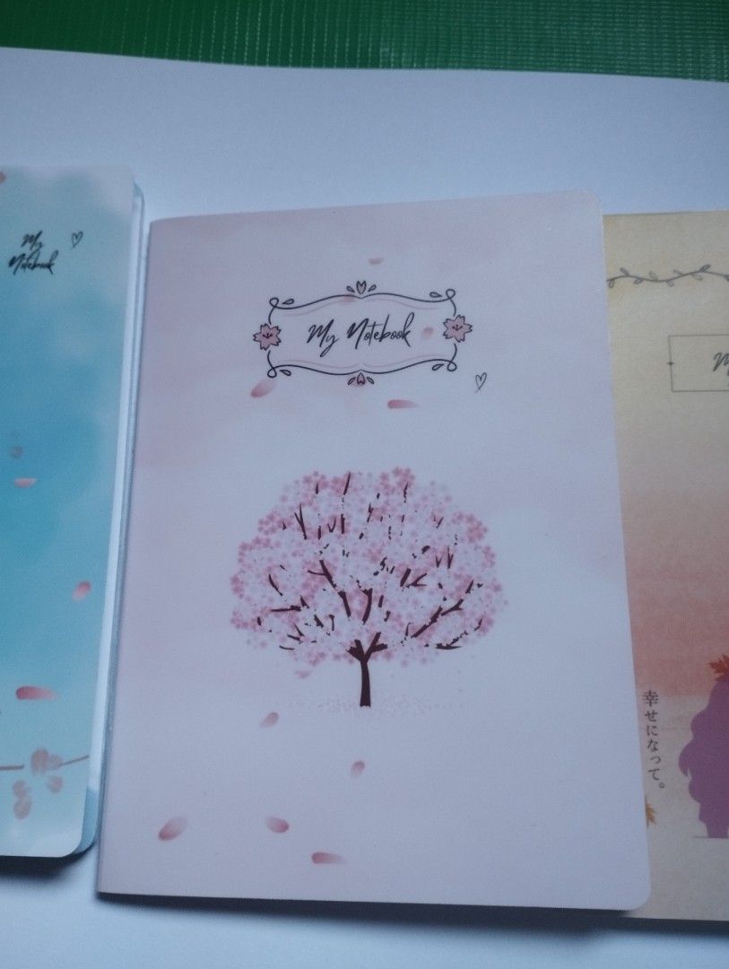 Cute Cherry Blossom Notebook Japanese Aesthetic Diary (Category: Stationery & School Supplies) located in San Mateo. Submitted by diana_01.tree (Listing ID 1470350755, Image 1). Description: - Cover: Soft pink with a charming cherry blossom tree illustration, pocket size - Back: Features Japanese text and a cute small heart - Pages: Pretty floral borders at the top, watercolor wash, and with designs inside pages - Design: Slim and lightweight, ea
