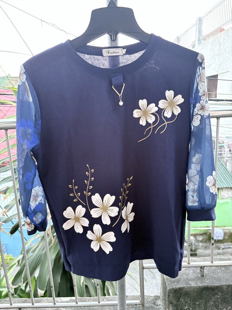Dark Blue Floral Sheer Sleeve Blouse (Category: Blouses) located in Cavite. Submitted by earthread (Listing ID 1470454401, Image 1). Description: - Color: Dark blue with white and gold floral prints - Sleeves: Sheer patterned sleeves - Neckline: Round neck with a decorative pendant - Fit/Material: Lightweight, comfortable everyday wear - Styling: Easy to match with jeans or skirts.