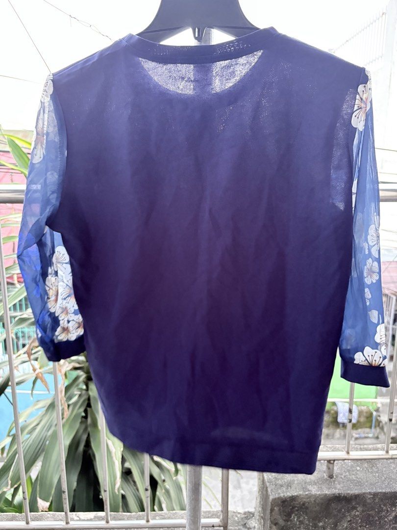 Dark Blue Floral Sheer Sleeve Blouse (Category: Blouses) located in Cavite. Submitted by earthread (Listing ID 1470454401, Image 2). Description: - Color: Dark blue with white and gold floral prints - Sleeves: Sheer patterned sleeves - Neckline: Round neck with a decorative pendant - Fit/Material: Lightweight, comfortable everyday wear - Styling: Easy to match with jeans or skirts.