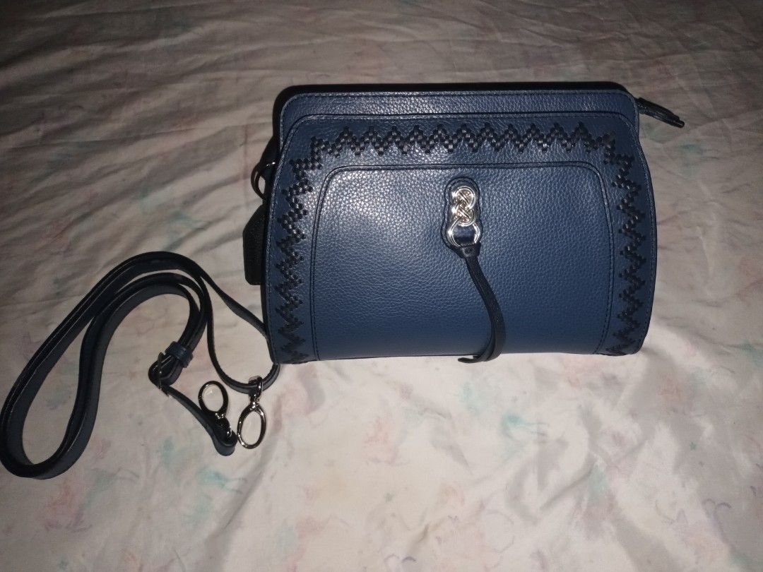 Dark blue structured crossbody handbag with patterned lining and strap (Category: Cross-body Bags) located in Manila. Submitted by lemlem_10 (Listing ID 1470370226, Image 1). Description: Dark blue faux leather crossbody bag. Textured pebble finish with decorative contrast stitching on the front flap and silver-tone hardware lock. Includes a matching adjustable shoulder strap with metal clips. Interior features patterned fabric lining with multip