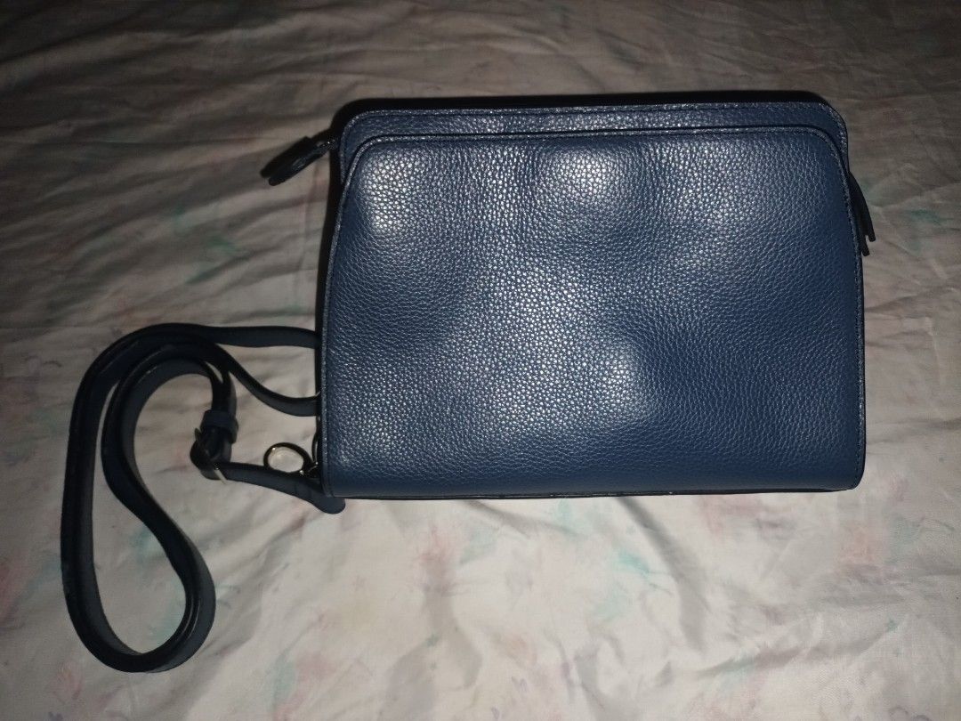 Dark blue structured crossbody handbag with patterned lining and strap (Category: Cross-body Bags) located in Manila. Submitted by lemlem_10 (Listing ID 1470370226, Image 2). Description: Dark blue faux leather crossbody bag. Textured pebble finish with decorative contrast stitching on the front flap and silver-tone hardware lock. Includes a matching adjustable shoulder strap with metal clips. Interior features patterned fabric lining with multip