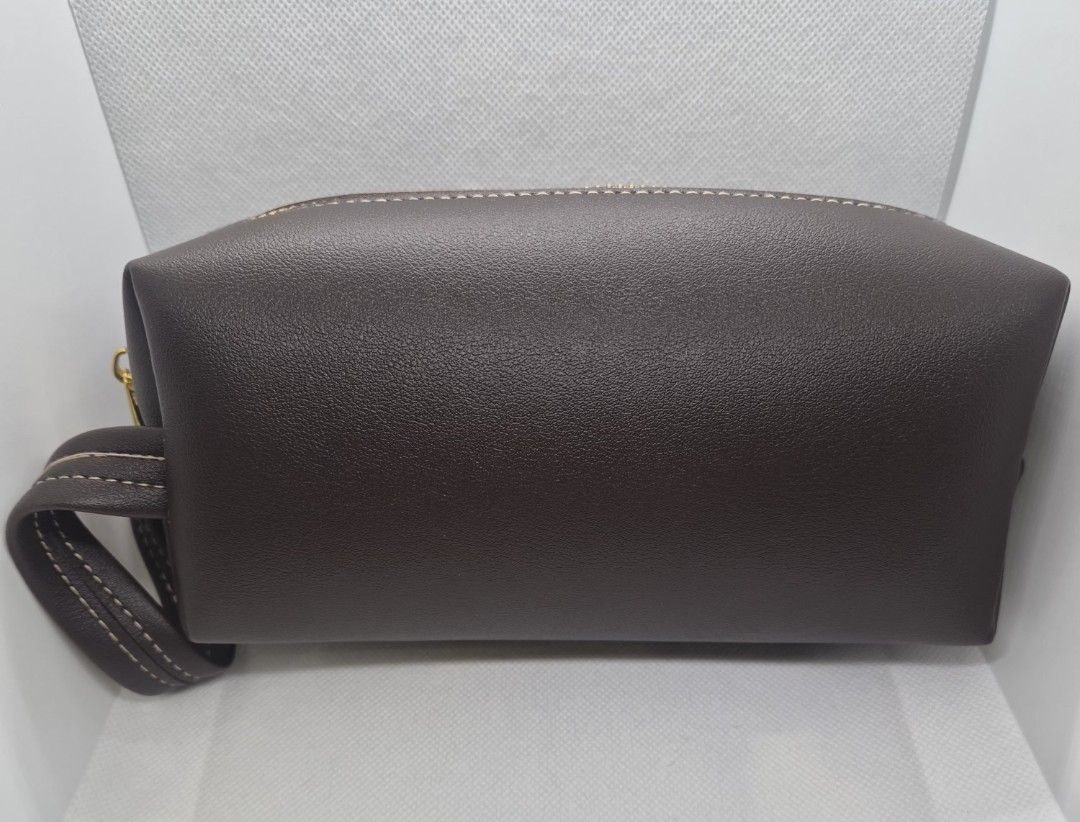 Dark Brown Leather Toiletry Pouch with Wrist Strap (Category: Purses & Pouches) located in Manila. Submitted by prelovedbyc.hannah (Listing ID 1470359051, Image 2). Description: - can be Free upon purchase of Dior cosmetic set - Color/Material: Dark brown faux leather with a stylish textured finish - Accents: Elegant contrast stitching and gold-tone top zipper - Portability: Includes a matching detachable wrist strap - Interior: Spacious with dar