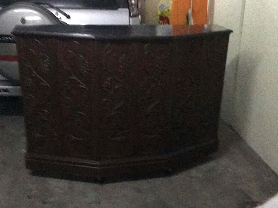 Dark Wood Carved Panel Counter (Category: Shelves, Cabinets & Racks) located in Caloocan City. Submitted by maynaito (Listing ID 1470432452, Image 1). Description: - Solid dark wood construction - Detailed floral carvings on front panels - Unique curved multi-sided shape - Smooth dark top surface - Heavy, sturdy, and durable - Perfect for shops, offices, or home bars - Pick up only due to size and weight.