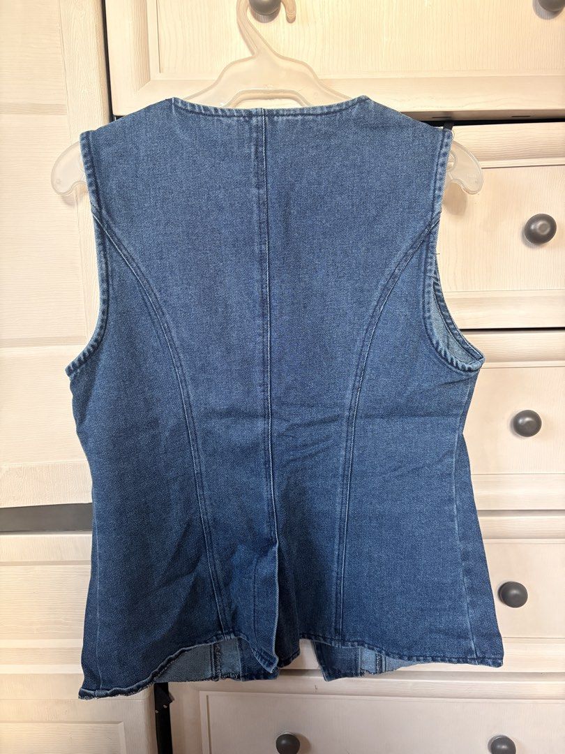 Denim vest sleeveless top (Category: Sleeveless) located in Makati City. Submitted by iu__00 (Listing ID 1470444098, Image 2). Description: - Style: Blue denim vest with a flattering fitted silhouette - Size: Medium - Neckline & Finish: Round neckline with stylish contrast topstitching - Details: Brass-tone center buttons and two functional welt pockets - Edge: Trendy raw-edge hem - Fit: Sleeveless cut, ideal for casual layering.