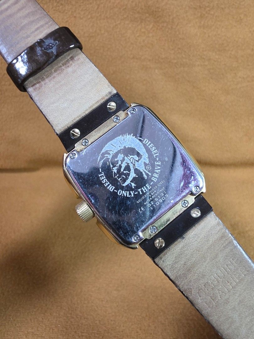 Diesel DZ5131 Textured Dial Leather Strap Watch (Category: Men's Watches) located in Rosales. Submitted by akumie30 (Listing ID 1470460649, Image 3). Description: - Brand: Diesel (Model DZ5131) - Dial: Textured square dial with a functional date window - Strap: Genuine dark brown leather with an adjustable standard buckle closure - Hardware: Brushed brass buckle and stainless steel case back with the iconic 'Only The Brave' logo - Condition: Norm